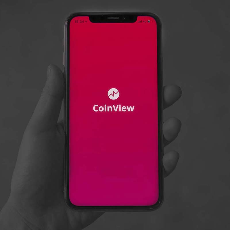 greyscale image of a hand holding a phone with a red app