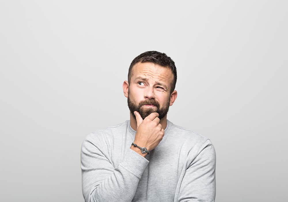 man with beard has his hand on chin and thinking