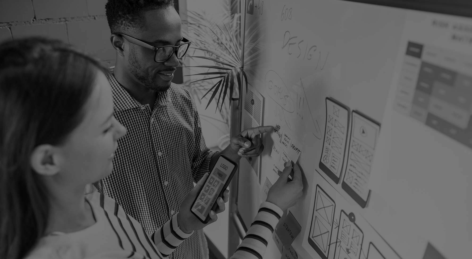 man and women lining up wireframes on whiteboard